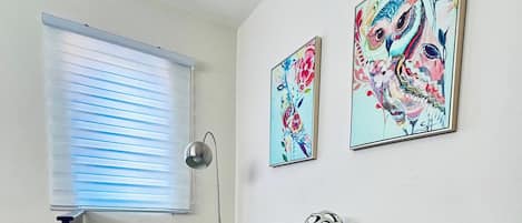 Une chambre moderne avec un lit, un bureau et deux œuvres d’art accrochées au mur.