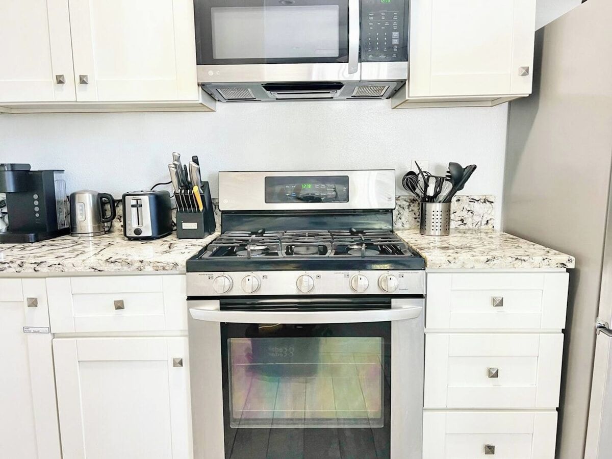 Una cocina equipada con microondas, estufa, horno y diversos electrodomésticos.