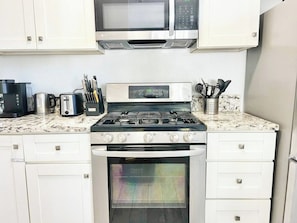 A kitchen with a microwave, stove, oven, and various appliances.