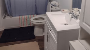 Ein Badezimmer mit Badewanne, Toilette, Waschbecken und Spiegel.