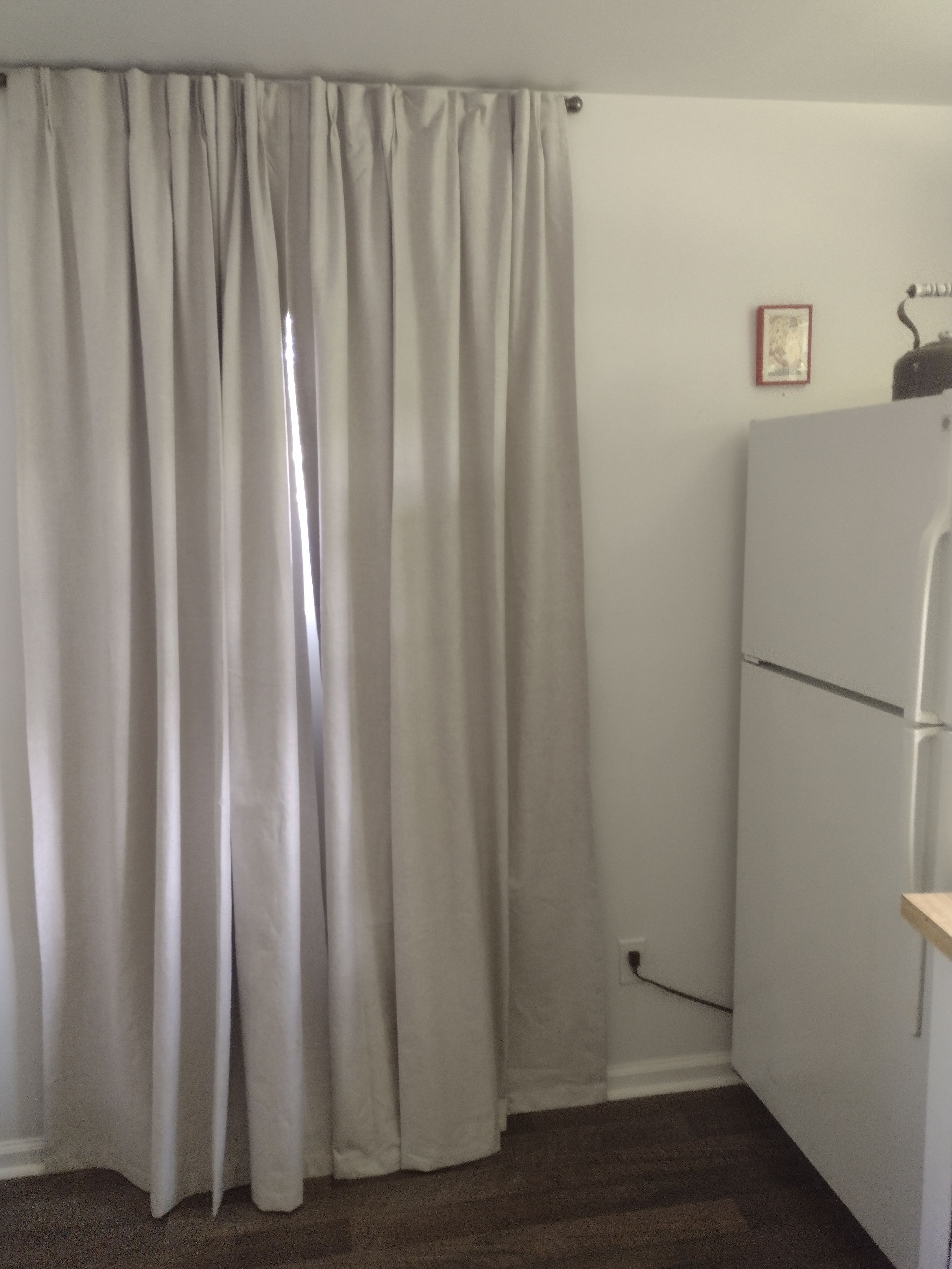 A room with a white wall, a white door, and a white refrigerator.