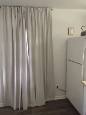 Ein Zimmer mit weißer Wand, weißer Tür und einem weißen Kühlschrank.