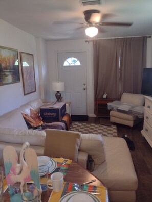 A living room with a sofa, a dining table set for two, a television, and a ceiling fan. - Private apartment in downtown Tallahassee. Private entrance. Access to backyard. (Tallahassee)