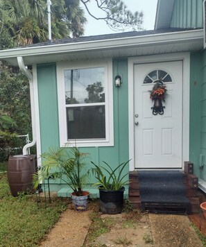 A house with a white door, a window, and a small porch area with potted plants. - Private apartment in downtown Tallahassee. Private entrance. Access to backyard. (Tallahassee)