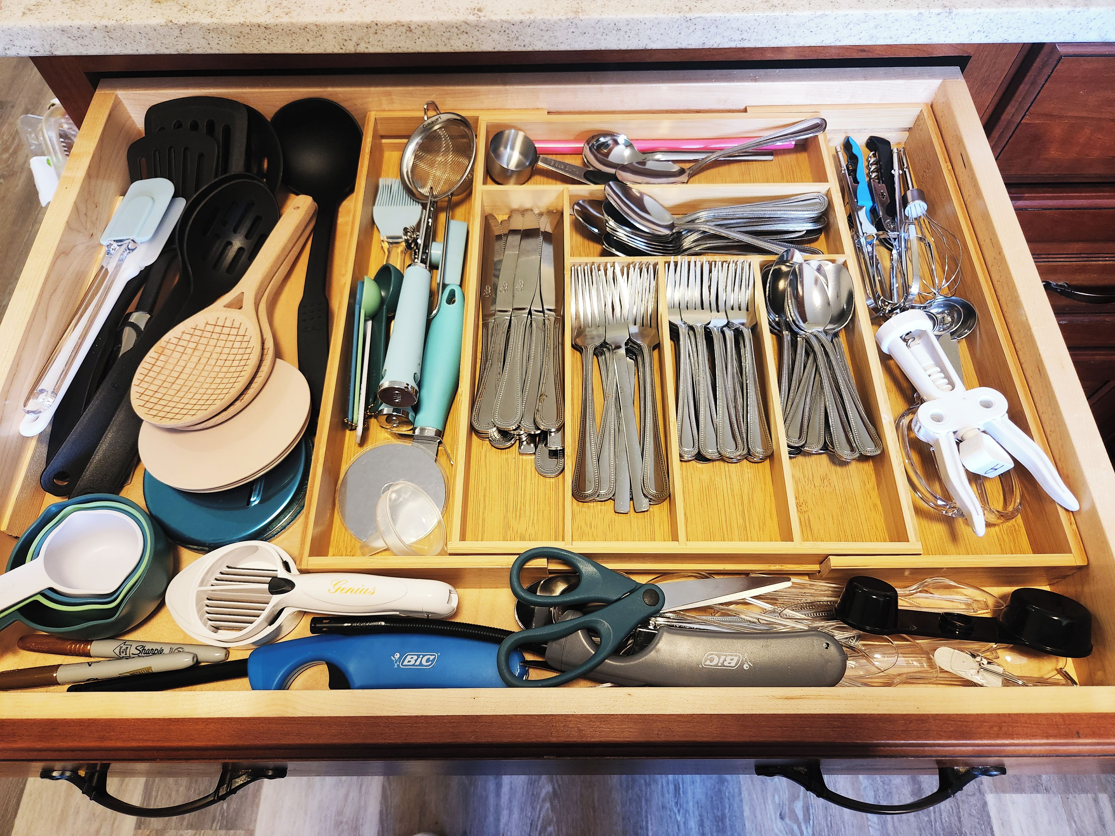 A drawer with various kitchen utensils and tools, including spatulas, tongs, and a grater.