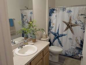 Une salle de bain équipée d’un lavabo, de toilettes et d’un rideau de douche orné de motifs représentant la vie marine.