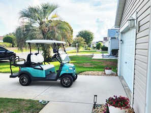 Ein Golfmobil steht auf einer Einfahrt mit einem Haus im Hintergrund.