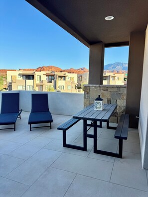 A balcony with two blue lounge chairs, a wooden table, and a lantern. - Peaceful Poolside Perfection!  4 bedroom 3-with King Beds & ensuites, 4-1/2 bath (Washington)