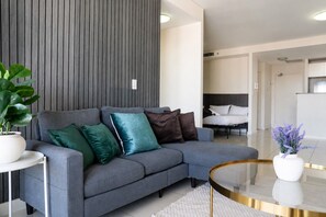 Una sala moderna con un sofá gris, una mesa de centro de vidrio y una planta en maceta.