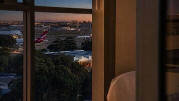 Vista desde una ventana con vista a un aeropuerto y un avión rojo en la pista.
