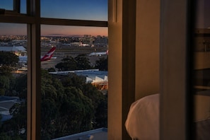 Vista desde una ventana con vista a un aeropuerto y un avión rojo en la pista.