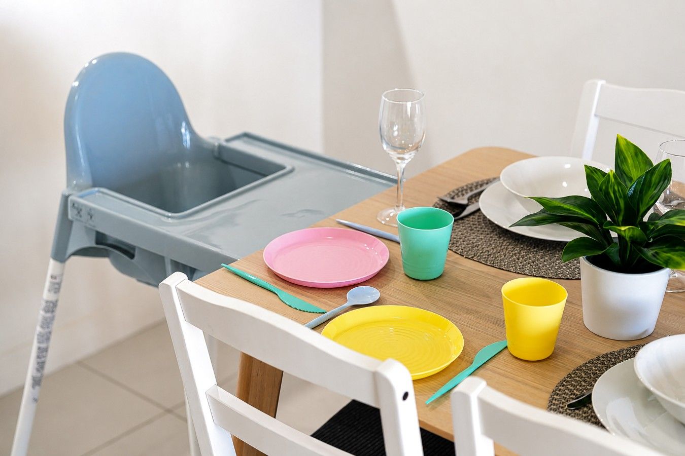 Un comedor con una mesa preparada para dos personas, con platos, cubiertos y una copa.