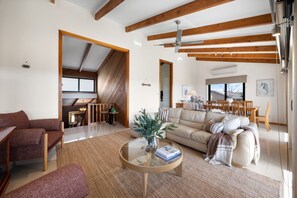 A spacious living area with a sofa, coffee table, and a dining area with chairs and a table. - Cedar By The Sea—Beach, River & Golf Getaway (Goolwa South)