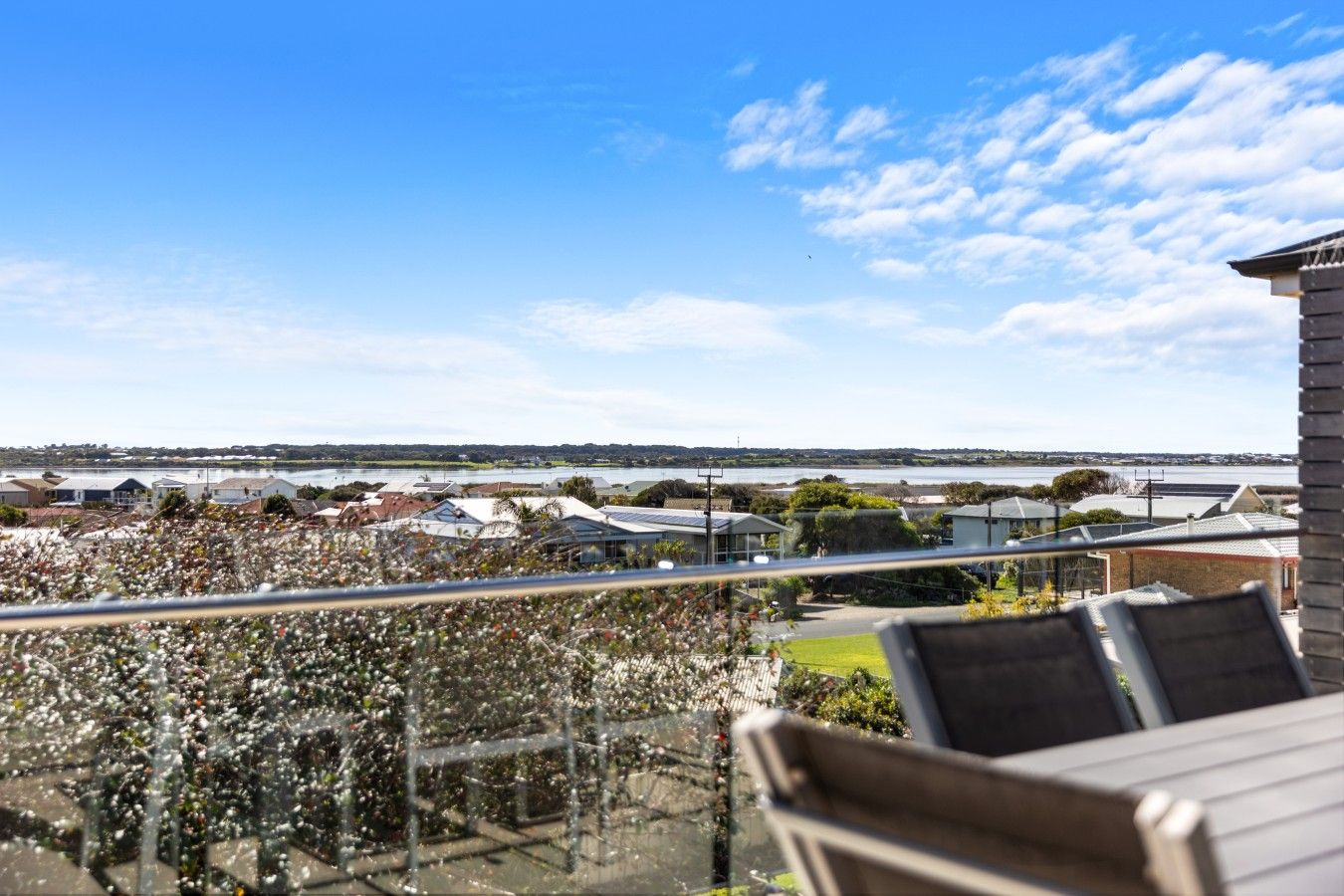 A balcony with a view of a residential area and a body of water.