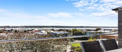 A balcony with a view of a residential area and a body of water.
