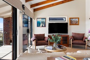 A living room with a TV, two armchairs, a coffee table, and a sofa. - Cedar By The Sea—Beach, River & Golf Getaway (Goolwa South)
