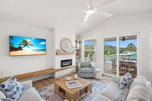 Ein modernes Wohnzimmer mit einem Flachbildfernseher, einem Kamin, einer gemütlichen Couch und Blick ins Freie.
