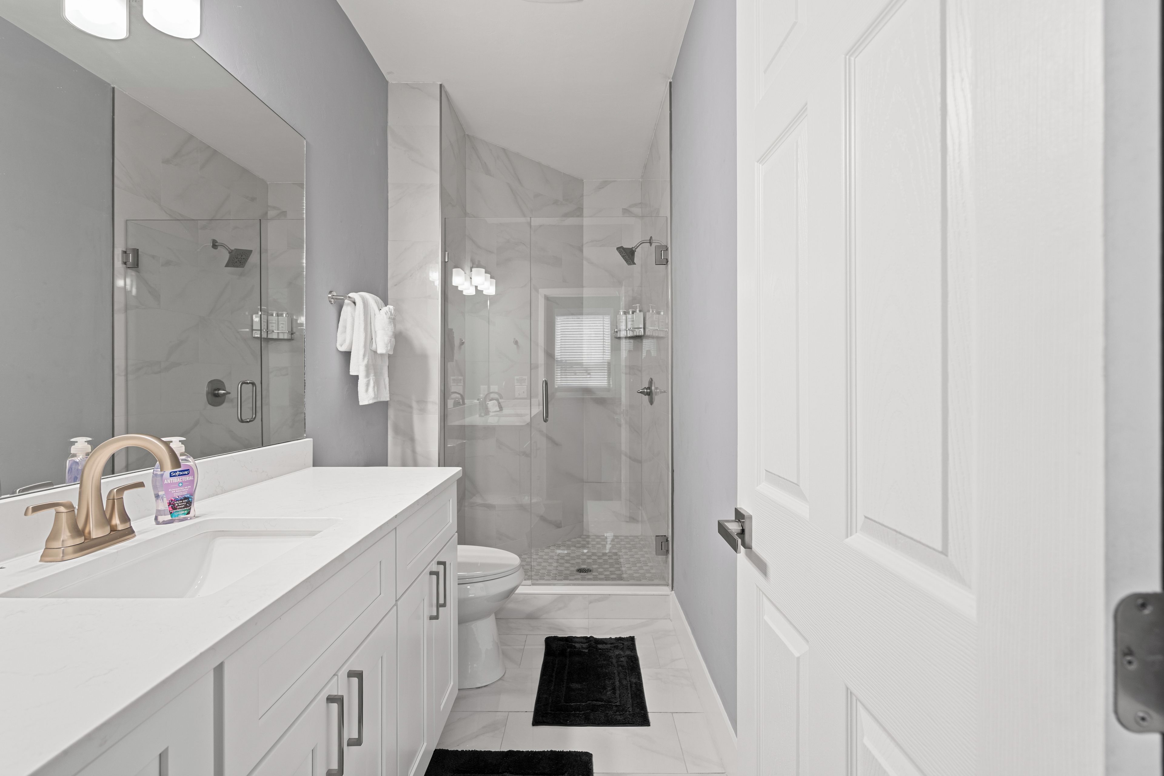 Un bagno moderno con un mobile lavabo bianco, cabina doccia in vetro e un water.