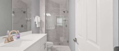 Un bagno moderno con un mobile lavabo bianco, cabina doccia in vetro e un water.