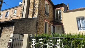A corner building with stone facade, a metal gate, and a small balcony. - Cozy, near Paris (Villeneuve-Saint-Georges)