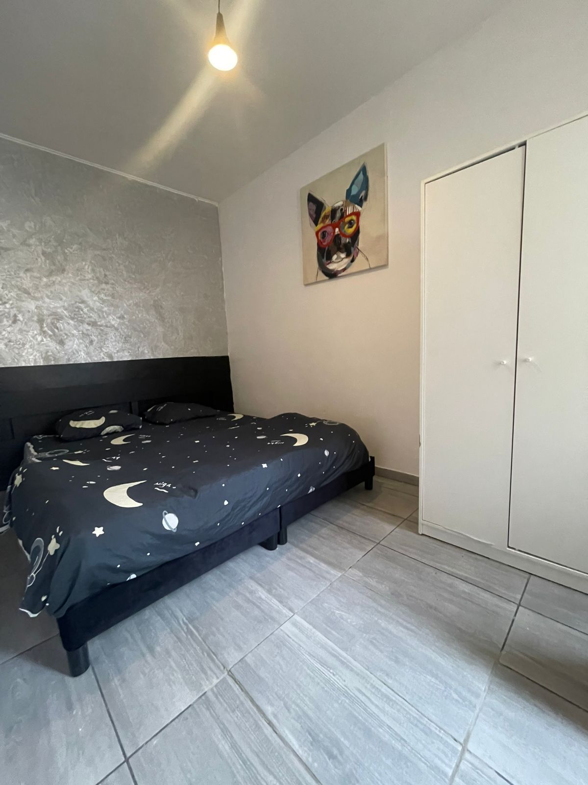 Ein Schlafzimmer mit einem Bett, einem Kleiderschrank und einem Bild an der Wand.