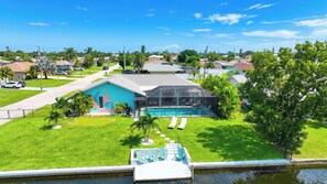 A residential property with a swimming pool, a covered patio, and a mural on the house. - VILLA CORAL CABANA – HEATED POOL | WATER VIEW | PUTTING GREEN | BOAT RENTAL + TOURS VOUCHER INCL. (Cape Coral)