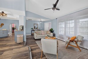A spacious living room with a ceiling fan, a sofa, a coffee table, and a dining area with a kitchen counter. - VILLA CORAL CABANA – HEATED POOL | WATER VIEW | PUTTING GREEN | BOAT RENTAL + TOURS VOUCHER INCL. (Cape Coral)