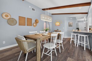 A dining area with a wooden table, white chairs, and a hanging light fixture. - VILLA CORAL CABANA – HEATED POOL | WATER VIEW | PUTTING GREEN | BOAT RENTAL + TOURS VOUCHER INCL. (Cape Coral)