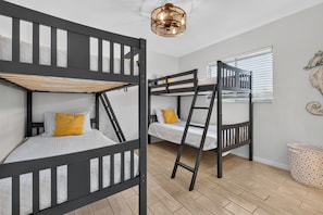 A room with bunk beds, a wooden floor, a window with blinds, and a polka-dotted trash bin. - VILLA CORAL CABANA – HEATED POOL | WATER VIEW | PUTTING GREEN | BOAT RENTAL + TOURS VOUCHER INCL. (Cape Coral)