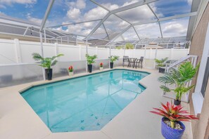 A clear blue pool with a white deck, surrounded by potted plants and outdoor furniture. - Peaceful 3BR 2BTH Villa | Private Pool | Game Room | Champions Gate Area (Davenport)