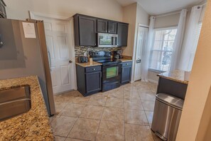 A compact kitchen with a refrigerator, microwave, stove, and oven. - Peaceful 3BR 2BTH Villa | Private Pool | Game Room | Champions Gate Area (Davenport)