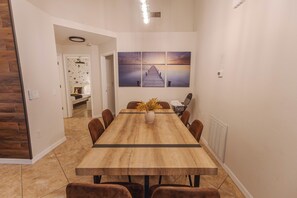 A dining area with a long wooden table, six chairs, and a vase with yellow flowers. - Peaceful 3BR 2BTH Villa | Private Pool | Game Room | Champions Gate Area (Davenport)