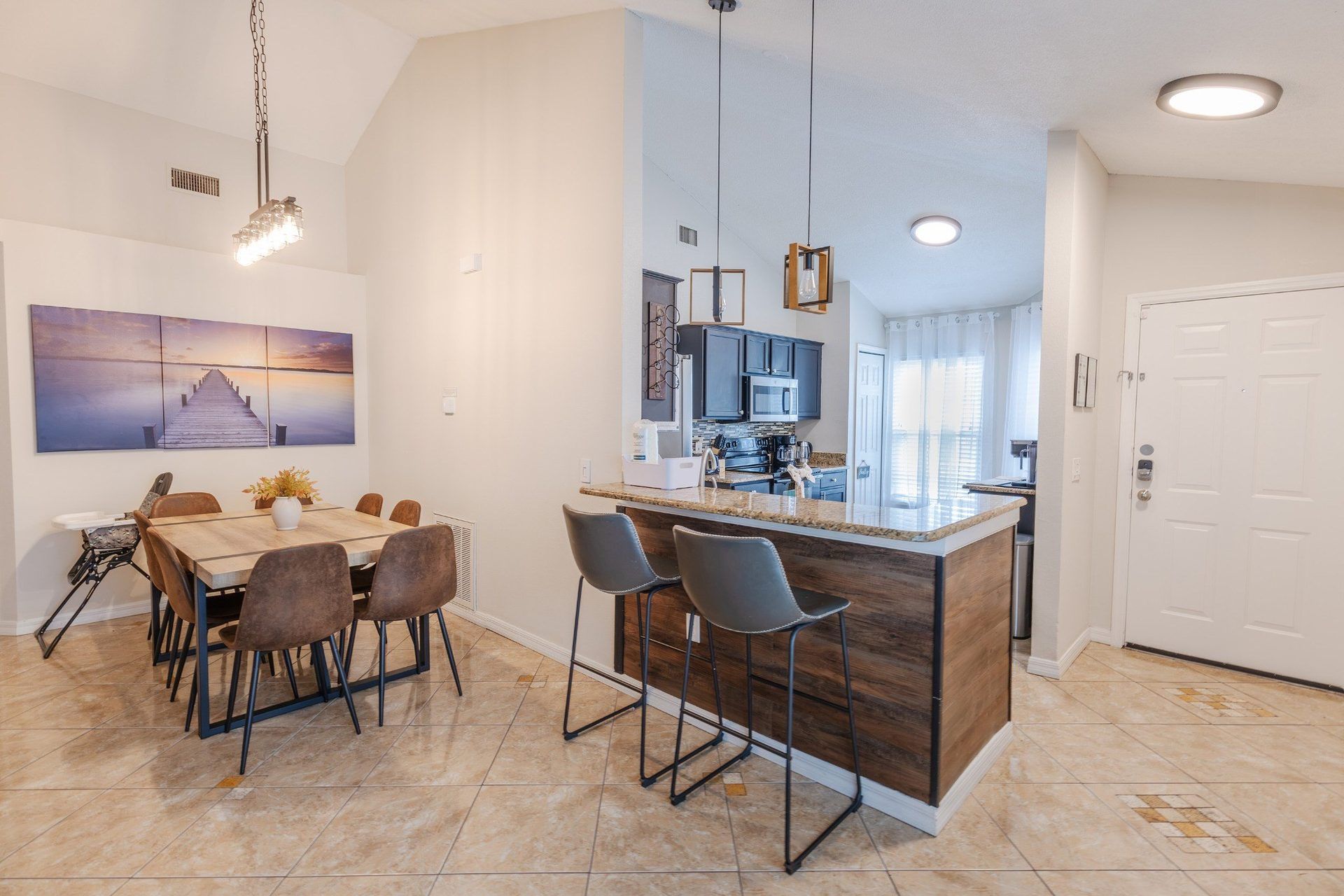 A modern kitchen with dark cabinetry, a central island, and pendant lighting.