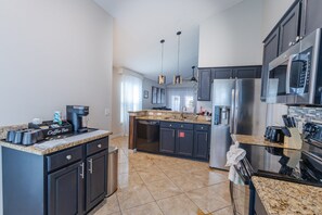 A modern kitchen with dark cabinets, stainless steel appliances, and a coffee bar. - Peaceful 3BR 2BTH Villa | Private Pool | Game Room | Champions Gate Area (Davenport)