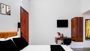 Une chambre d’hôtel comprenant un lit, un bureau avec une chaise, une télévision et une armoire en bois.