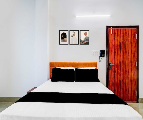 Una habitación de hotel con una cama, una puerta de madera y tres cuadros en la pared.