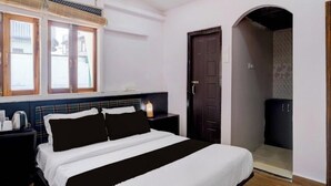 Une chambre à coucher comprenant un lit, des tables de chevet, une fenêtre et une porte donnant sur une salle de bain.