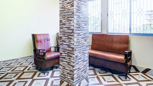 Une pièce avec un sol à motifs, une haute colonne, un banc rembourré et une chaise.