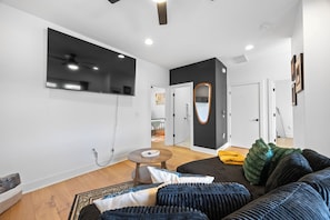 Ein modernes Wohnzimmer mit einer Couch, einem runden Couchtisch und einem Spiegel an der Wand.