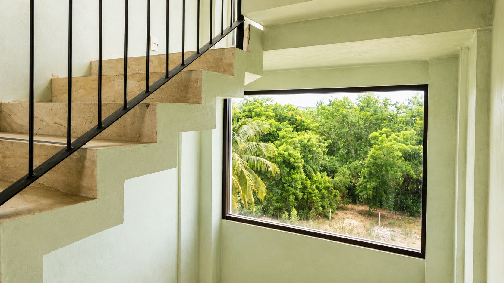 A staircase with a view of a lush green landscape through a window.