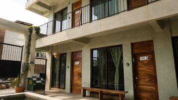 Un edificio con varias puertas de madera, con los números 101 y 102, y una banca en el exterior.