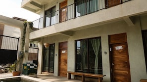 A multi-story building with a balcony, wooden doors, and a bench outside. - CASA AMOR ZIKATELA (Colotepec)