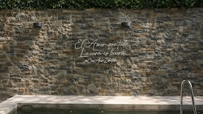 A stone wall with a quote in Spanish and a hashtag. - CASA AMOR ZIKATELA (Santa Maria Colotepec)