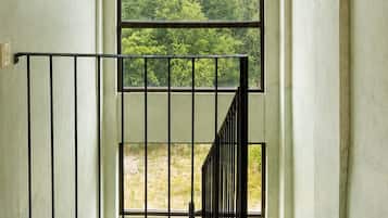 A staircase with a view of greenery outside, a hanging light fixture, and a metal railing.
