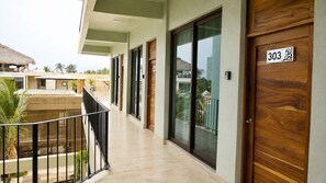 A hotel corridor with a wooden door labeled '303' and a balcony with a railing. - CASA AMOR ZIKATELA (Colotepec)