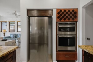 Una cocina con un refrigerador de acero inoxidable, un horno empotrado y un microondas.