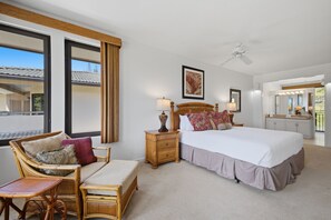 A hotel room with a bed, a chair, a nightstand, a lamp, a ceiling fan, and a window with curtains. - Kapalua 14T3 | Spacious 3BR Maui Vacation Home (Lahaina)