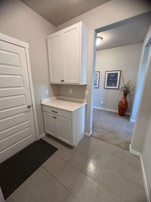 A hallway with a white door, a white cabinet, and a vase with plants. - Tabor & Timber - 6BR Retreat w/ Hot Tub, Huge Basement + Fire Pit (Berthoud)