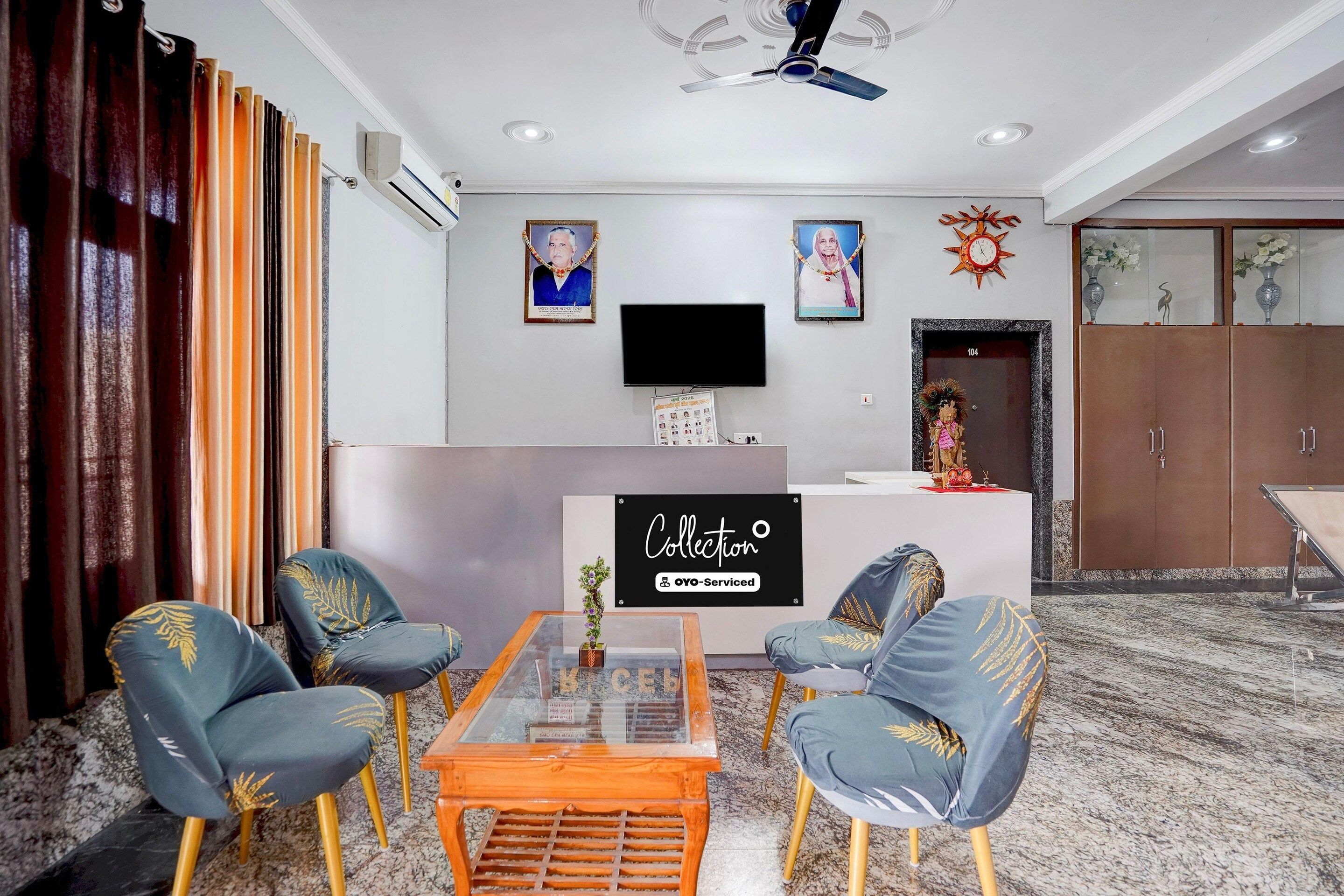 Un soggiorno moderno con un tavolino in vetro, due poltrone blu decorate con motivi a foglia d'oro, un televisore a schermo piatto e un pannello decorativo sulla parete.