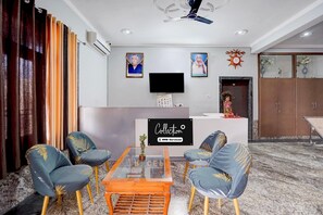 Una sala de estar moderna con una mesa de centro de vidrio, dos sillones azules con detalles dorados, un televisor de pantalla plana y un cartel decorativo en la pared.